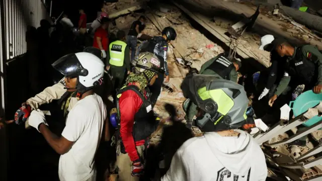 Emergency services work at the site of a collapsed building after an earthquake in Caracas