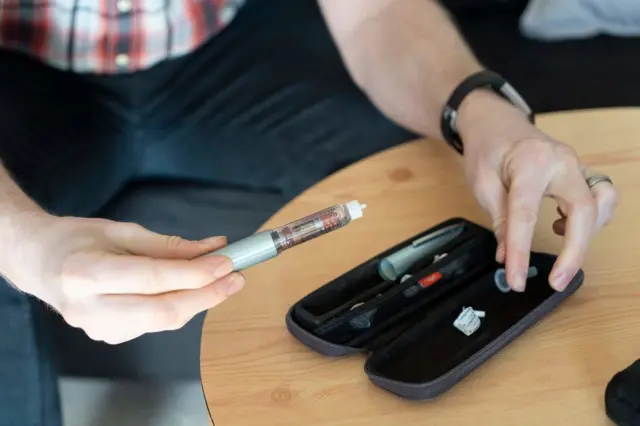 A diabetic man prepares his insulin pen to inject himself