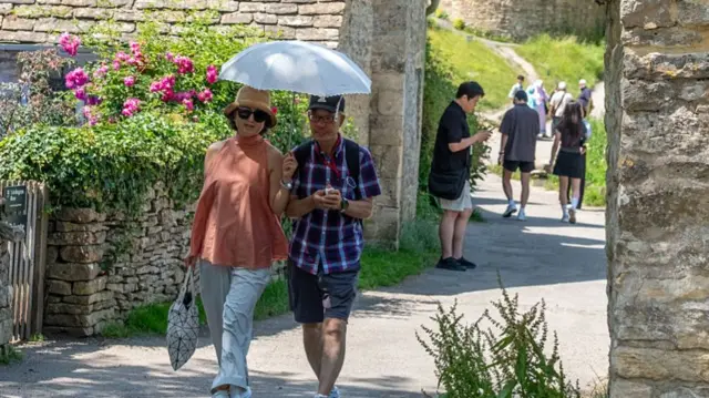 Visiting tourists use an umbrella to shelter from the sunshine.