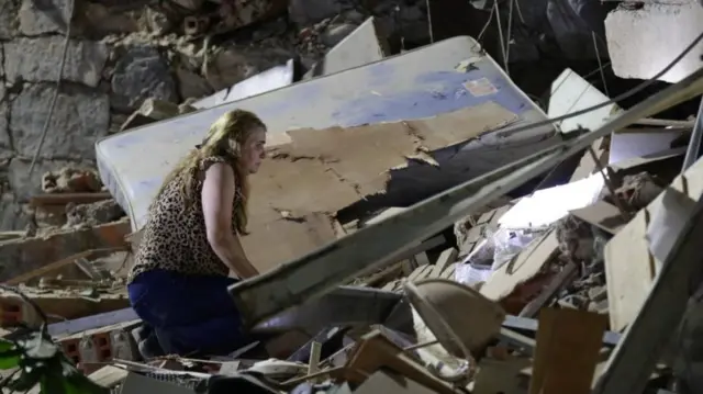 A woman kneeling on a pile of rubble from a collapsed building in Caracas