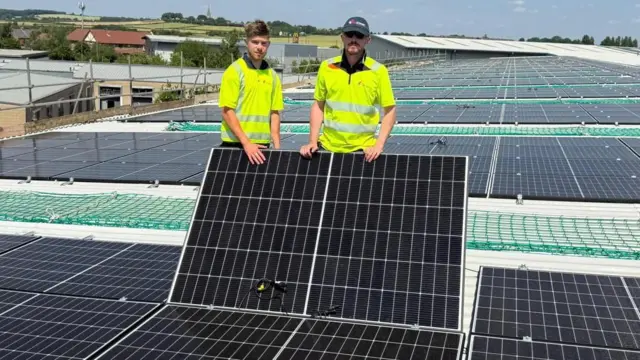 Two men standing on solar panel roof