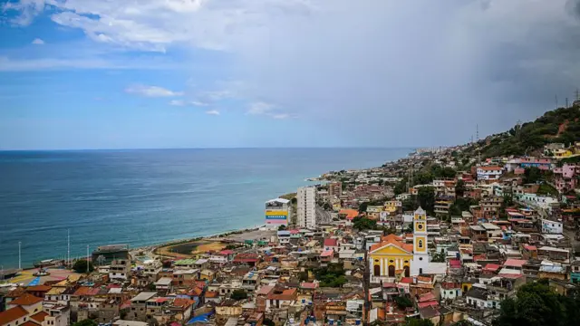 A view over a town with lots of small colourful houses on a hillside in front of a nice blue sea