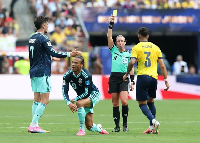 Referee Tori Penso issues a yellow card to Piero Hincapie