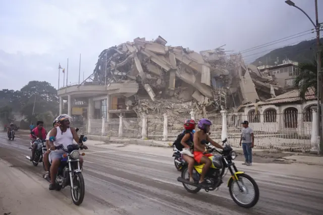 Motorcyclists pass a damaged building in Caracas