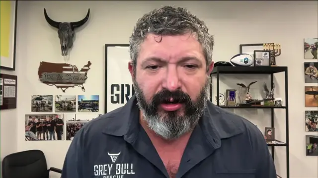 Man with a beard wearing a grey shirt with the logo Grey Bull Rescue