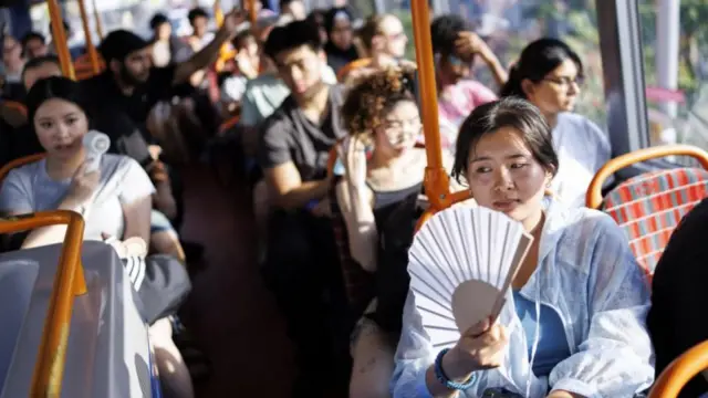 A person uses a fan to cool down on a TfL bus service in east London on 24 June