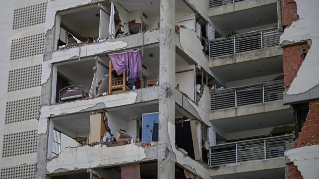 A damaged apartment building where walls have fallen off and you can see into the rooms of peoples homes