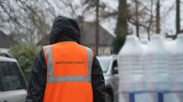 A person in a high vis jacket. Their back is turned.