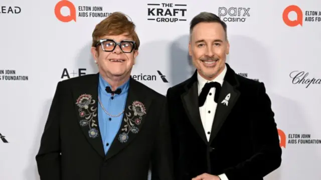 Elton John and David Furnish standing together on a red carpet
