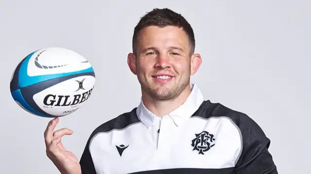 Elliot Dee spins the ball on his fingers while wearing a Barbarians jersey