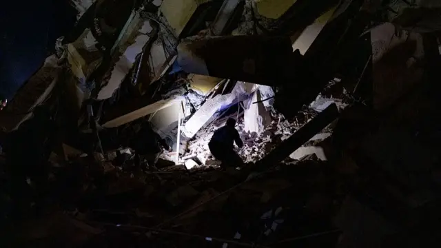The silhouette of a person illuminated in a destroyed building