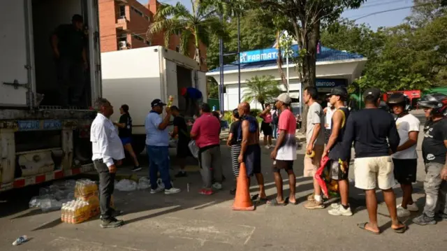 A queue of people wait to receive supplies