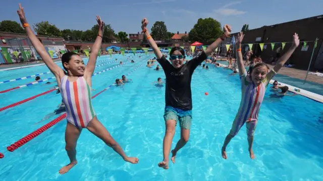 Siblings Hayley and Em Vitiello, and their friend Rioghnach Iadicicco star jump into the water at Charlton Lido