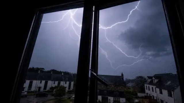 Forked lightning seen at night through window panes from a house in Cornwall