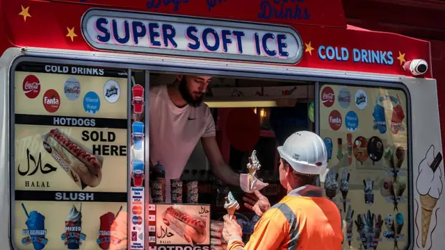 A construction worker buys an ice cream from an ice cream van