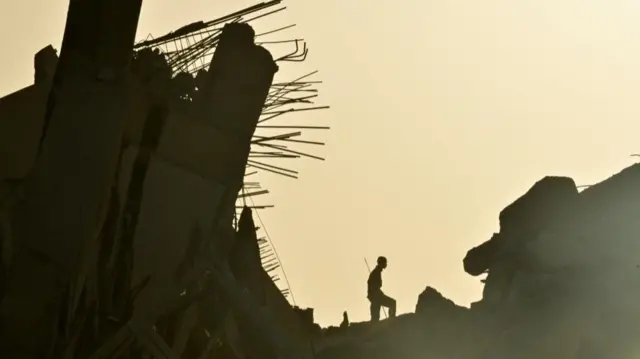 A person stands silhouetted among the remains of a damaged building in La Guaira