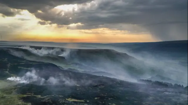 A photo showing a large area of charred moorland and woodland