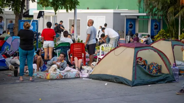 A man lies on a mattress with a dog among several people on a pedestrianised area of Venezuela