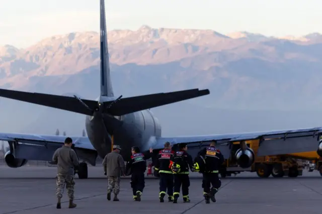 Chilean search team walk to a plane ahead of their departure for Venezuela