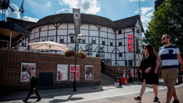 People walk past the Globe theatre in central London on a sunny day