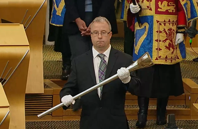 Robert White carrying the Mace into the chamber