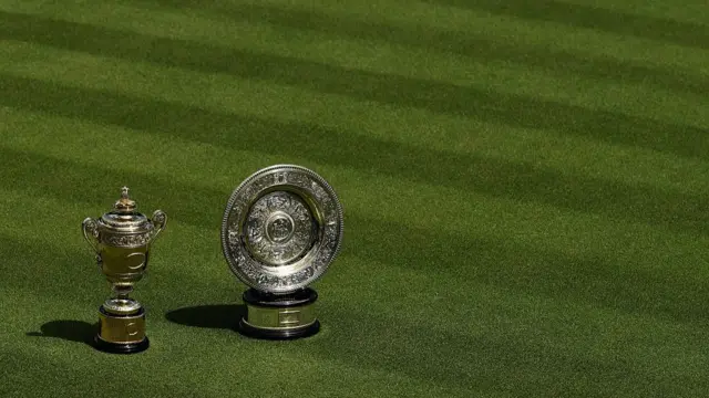 Wimbledon men's and women's trophies sit on grass on centre court