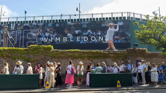 People stand in queue outside Wimbledon sign