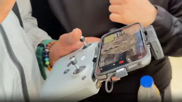 A man controls a drone as people watch