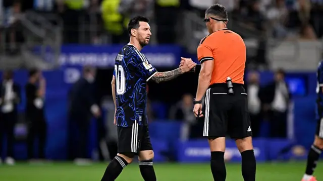 Lionel Messi shakes hands with the referee