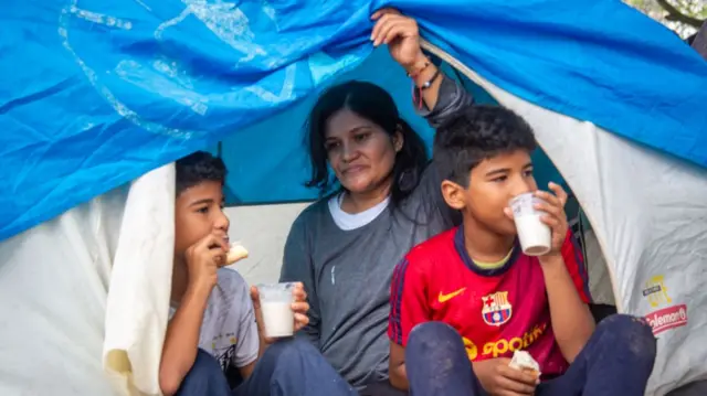Maria Sandoval sheltering in tent with her 10-year-old twin sons
