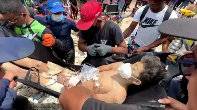 Teenage boy on stretcher having been pulled from rubble
