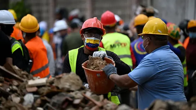 Workers remove debris from a collapsed building in the San Bernardino neighborhood of Caracas