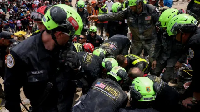 Members of a US rescue team work to assist a person trapped under the rubble of a building in La Guaira