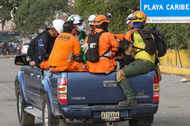 rescue workers travel in the back of a pick-up truck