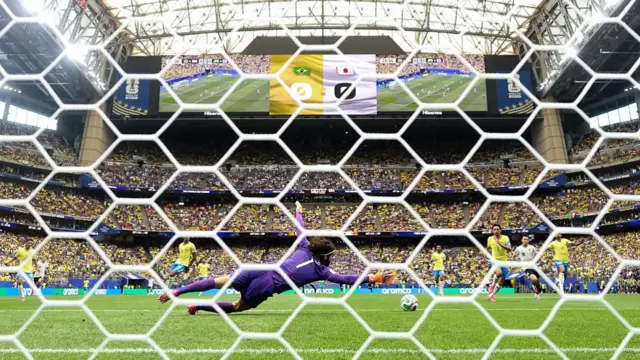 HOUSTON, TEXAS - Alisson #1 of Brazil concedes a first goal to Kaishu Sano #24 of Japan during the FIFA World Cup 2026 Round Of 32 match between Brazil and Japan.