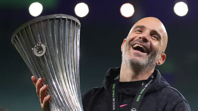 Enzo Maresca laughs holding the Conference League trophy