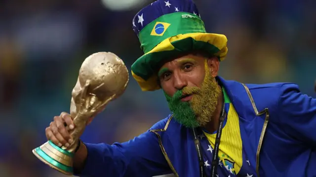 A fan of Brazil with a painted beard and replica World Cup trophy