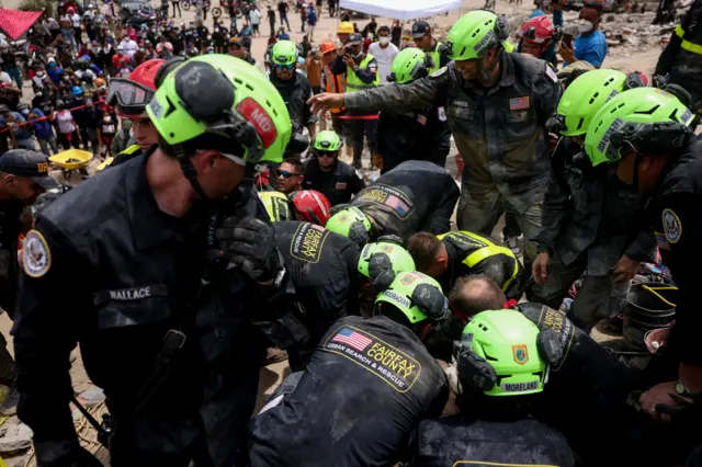 US rescue teams in Fairfax County Urban Seach and Rescue jackets work on a teenager pulled out of the rubble a crowd observing in the background