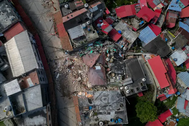 An aerial shot shows a destroyed building in El Junquito in Venezuela. It is surrounded by the red roof tops of similar buidlings