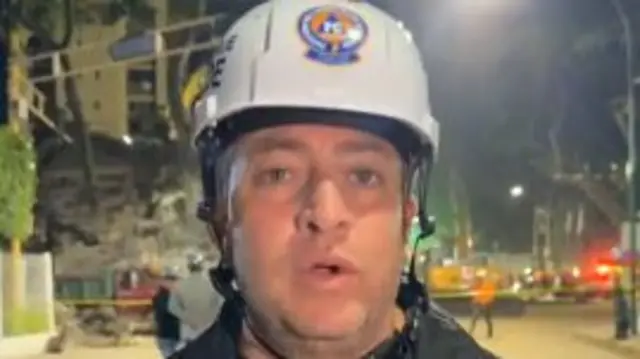 Gustavo Duque speaking to the camera, wearing a helmet and wearing a black jacket which says: "Chacao alcalde"