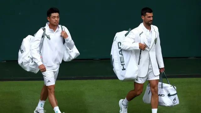 Novak Djokovic and Yibing Wu walk onto court