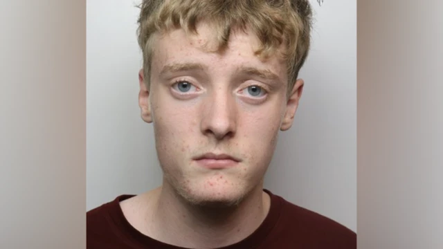 A police mugshot of a man with short blonde hair and a dark t-shirt