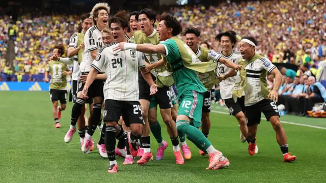 Kaishu Sano #24 of Japan celebrates with teammates after scoring the team's first goal during the FIFA World Cup 2026 Round Of 32 match between Brazil and Japan.