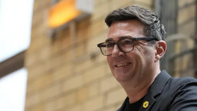 Andy Burnham smiles as he speaks during a speech in Manchester