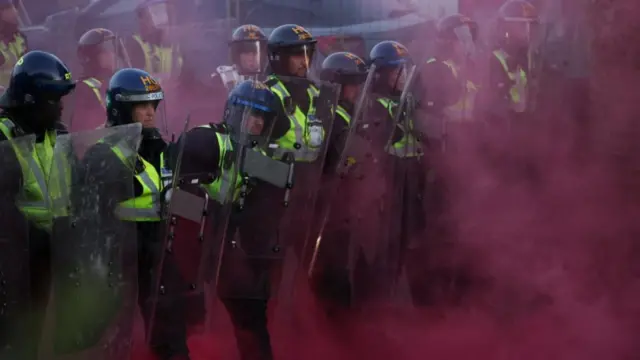Police officers stand guard amid colored smoke during a demonstration following the conviction of Vikrum Digwa for the murder of student Henry Nowak, in Southampton, Britain, June 2, 2026.