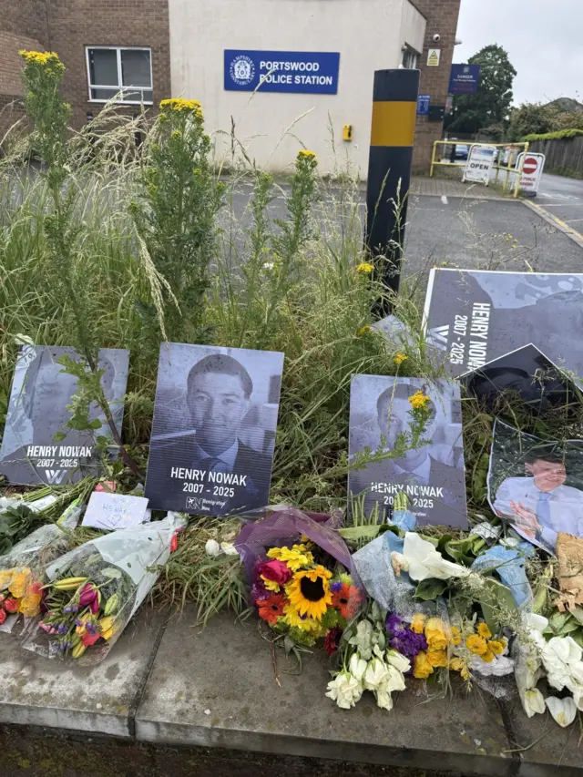 Memorial for Henry Nowak, which includes black and white photos of him and bouquets of flowers. These are laid in front of Portswood Police Station.