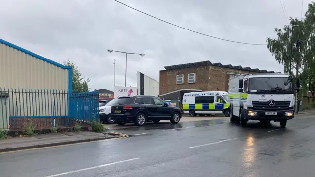 Police vehicles - including a bomb disposal van - leave the factory site