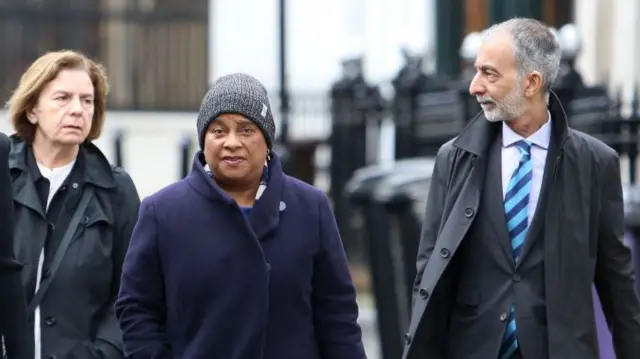 Doreen Lawrence walking in between a man and woman on a street