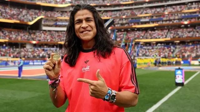 Actor and footballer Cristo Fernandez demonstrates the World Cup coin before the opening match of the last 32 between South Africa and Canada