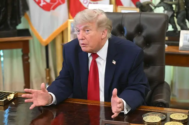 Donald Trump sitting behind the desk in the Oval Office